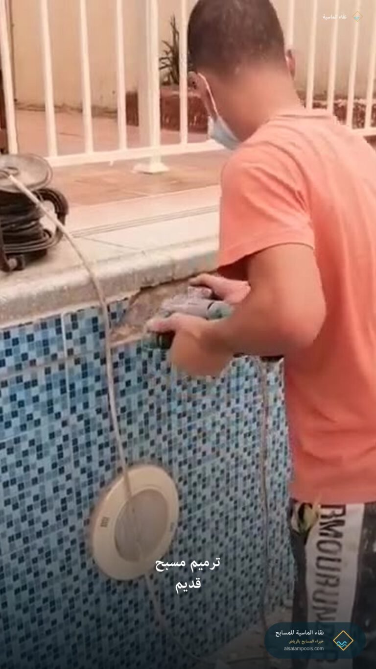 عامل يرمم حافة مسبح قديمة بجانب البلاط المتضرر